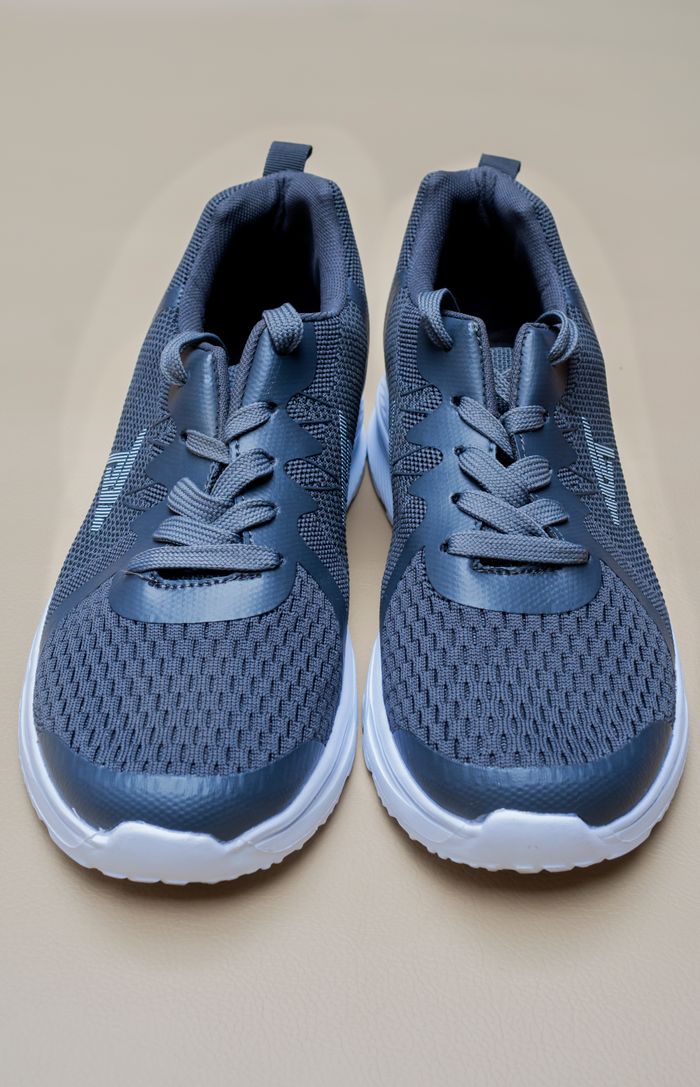Close-up of stylish gray athletic shoes with white soles on a neutral background.
